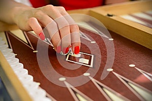 Backgammon bone square white dice for gambling with blurred background. woman with red nails is playing backgammon