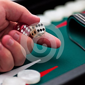 Backgammon player's hand holding the dice square