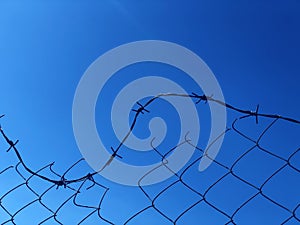 Background of a barbwire fence against a blue sky