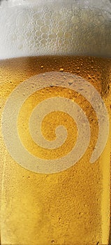 Background beer with foam in glass with water drops and beautifully rising bubbles