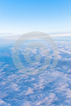 Background of a blue heavenly sky with fluffy dense clouds, top view from an airplane, vertical frame. Sky Gradient