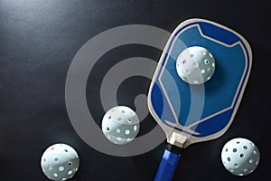 Background with blue pickleball paddle and balls on black