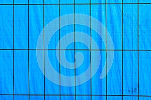 background of blue plastik foil with metal grid in foreground