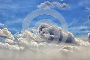 Background. Blue sky with a gray thundercloud in the middle, which dips into white feathery fluffy clouds. Fog rises from below. D