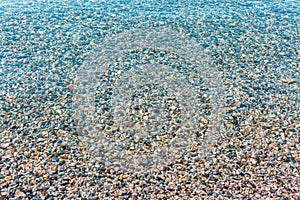 Background of blurred bright colorful sea stones under water. Iridescent sunlight on the stones. Toned photo