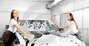 Background blurred hand hold sponge over black car for washing white foam