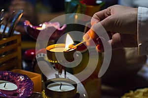 Background blurred woman's hand lights a candle in a candlestick with a match