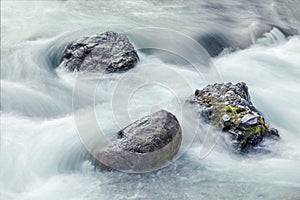 Background with bolders in a river with smooth water