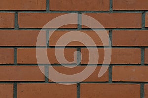 The background of a brick wall, made of red, ceramic bricks.