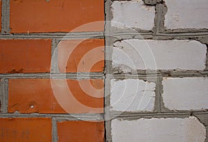 Background of a brick wall where half is lined with red brick and half is white. A brick of rare stones divides the wall