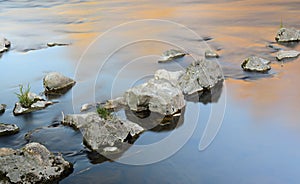 Background and calm picture with stones, which are arranged one behind the other in the very calm water and form a diagonal path,