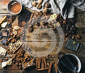 Background with chocolate, nuts and spices over wooden backdrop