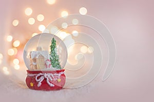 Background for a Christmas card in light pink with a souvenir snow globe