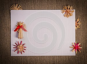 Background for Christmas greeting card- holiday straw decoration, red and claret textured paper