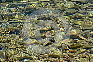 Background of clear water with soft sunny ripples and stones