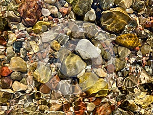 Background of colored river stones or pebbles under water. Top view. Clean and clear water