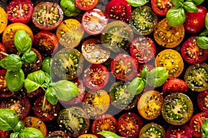 Background of colorful Cherry Tomatoes and basil leaves. Cutted and spiced tomatoes before cooking.Top view