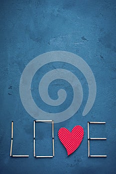 Background of concrete and blue paint plaster. On the texture matches arranged in the form of the word Love. In the middle o