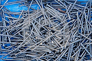 Background of construction metal nails close-up. The view from the top. One rusty nail was wedged between the rest of the chrome-