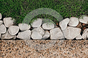 Background with the contrast of pebblestones white rocks and bright green grass