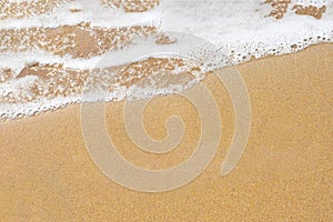 Background with copy space made of yellow sandy beach view of seashore with foamy wave.