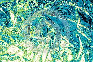 Background of crumpled foil with a reflection of green and blue