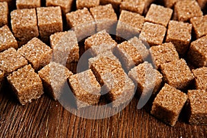 Background of cubes of brown sugar on a wooden table