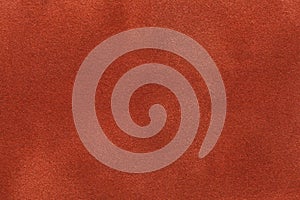 Background of dark orange suede fabric closeup. Velvet matt texture of ginger nubuck textile