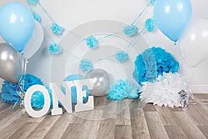 background decoration for birthday celebration with gourmet cake, letters saying one and blue balloons in studio