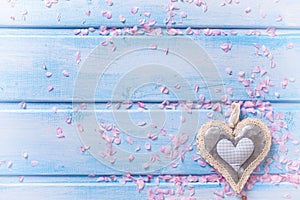 Background with decorative heart and pink petals on blue wood