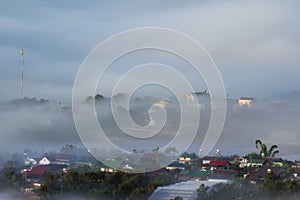 Background with dense fog and magic light at the sunrise. The coffee farm and small houses in brilliant sunshine