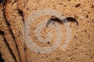 Background, detail and close-up shot of a few slices of German wholemeal bread, one on top of the other. A hole was cut in the