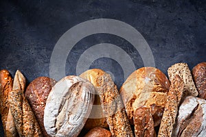 Background with Different Types of Bread on dark surface. Close up. Bakery concept. Empty space for text