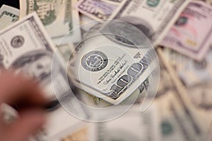 Background of dollars magnified under a magnifying glass held in hand. A magnifying glass magnifies a hundred dollar