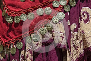 Background of draped gypsy shawls with decorative coin and bead fringe and distinctive weave for each piece - red and burgundy