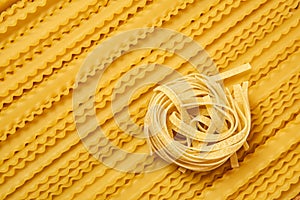 Background of dried pasta, tagliatelle and mafaldini