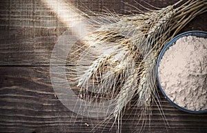 Background Dry wheat ears and flour on old wooden table