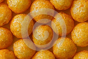 Background of extruded puff cheese balls from above.