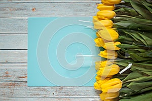 Background with flowers. Tulips in a bouquet white and yellow on a wooden blue background. Gifts for International Women`s Day,