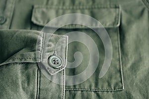 Background of folding sleeve of green jacket on pocket and buttonhole with seam line. Clothing detail. Top view. Copy, empty space