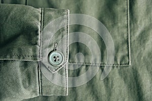 Background of folding sleeve of green jacket on pocket and buttonhole with seam line. Clothing detail. Top view. Copy, empty space