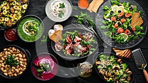 Background food and dishes. Salads, snacks and soups on black background.