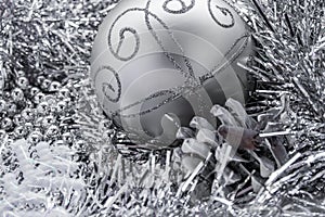Background in the form of Christmas-tree decorations - a large silver ball, a silvered cone and silver rain
