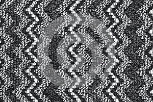 Background in the form of a woolen product with a pattern of alternating vertical black and white zigzags