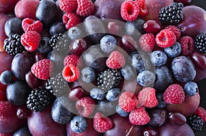 Background of fresh fruits and berries. Ripe blackberries, blueberries, plums, red berries, raspberries. Mix berries and fruits. T