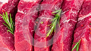 background of fresh raw sliced beef steaks, garlic, rosemary and