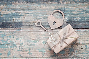 Background with gift box, small white flowers, lock-heart and key on old boards with shabby paint. Place for text.