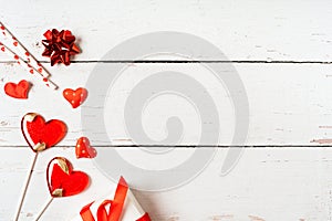 Background with gift, confetti and hearts lollipops with free space for text on wooden background. Valentines day