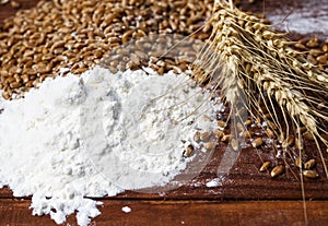 Background of Golden wheat grains with ears and white crumbling flour scattered on wooden table