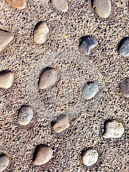 Background of granulated sand with an aerial view of separate pebbles of different shapes and ocher and gray colors. Backgrounds